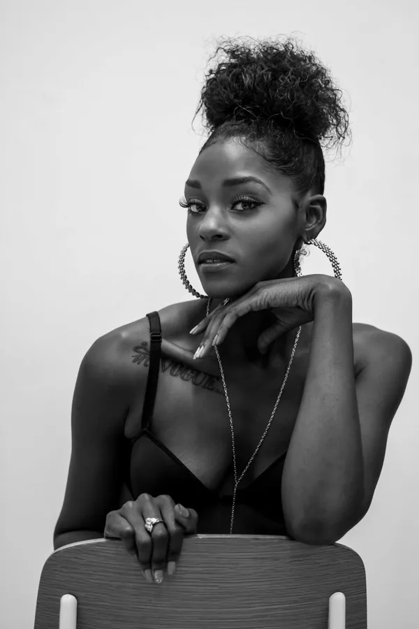 Black-and-white editorial portrait of a woman seated on a chair