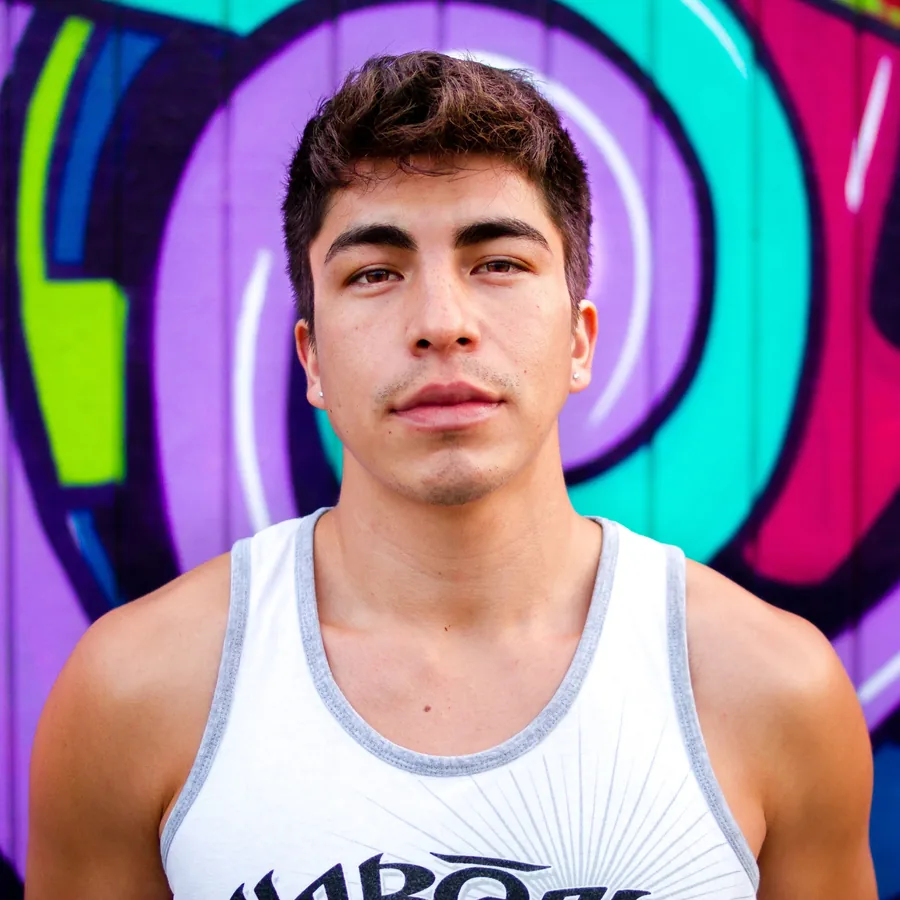 Editorial portrait of a young man against a vivid mural